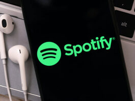 Spotify presenta sólidos resultados en el 3T 2025 Imagen del logo de Spotify en un móvil, junto a auriculares.